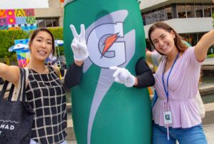 Two employees posing with drink mascot