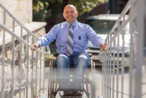Man in wheelchair coming toward camera and smiling
