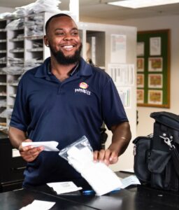 PepsiCo employee wearing a navy blue polo shirt is sorting papers in a mail room