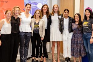 Group of nine women standing together with arms around each other